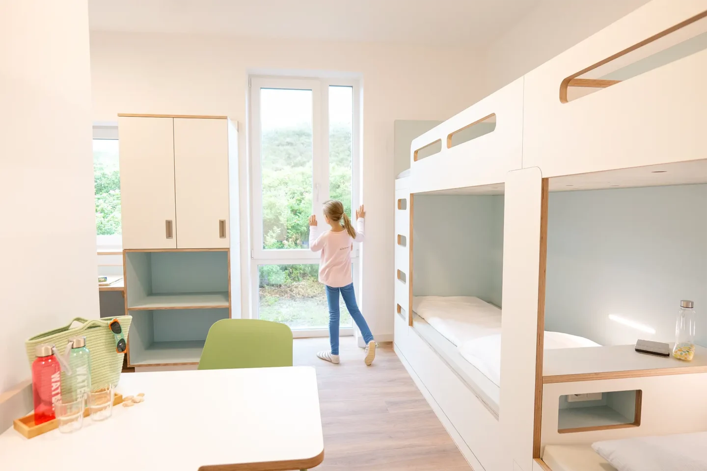 Mädchen steht am Fenster eines 4-Bett-Zimmers und schaut heraus.