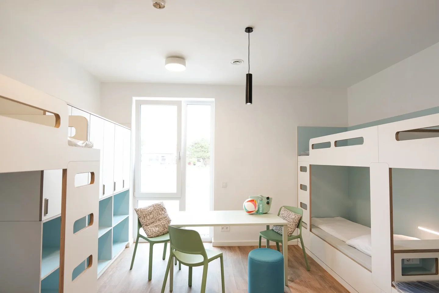 6er Zimmer mit Stockbetten und einem Gemeinschaftstisch mit Stühlen in der Mitte