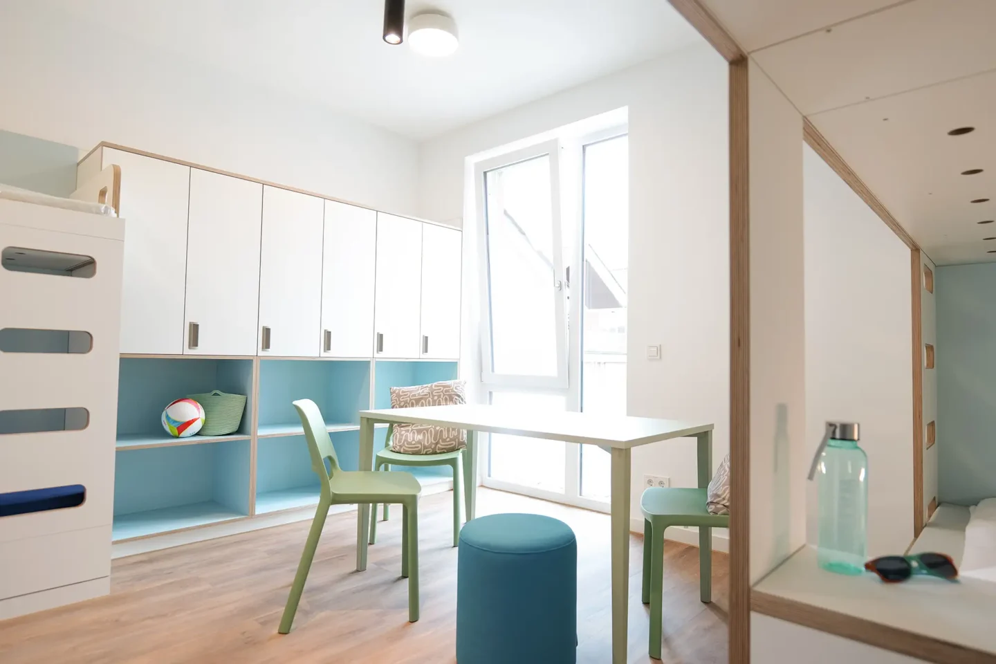 6er Zimmer mit Gemeinschaftsstisch, Stühlen und einem großen Schrank für Stauraum