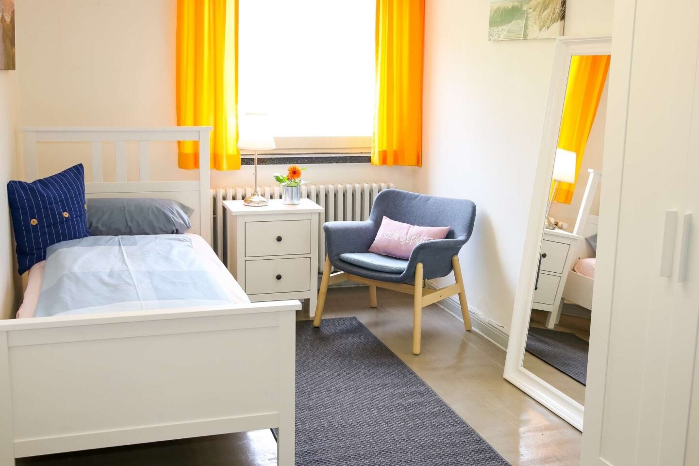 Helles, gemütliches Einzelzimmer für Betreuungspersonen in der Freiluftschule Bunthausspitze mit einer Sitzecke, Einzelbett und Kleiderschrank.