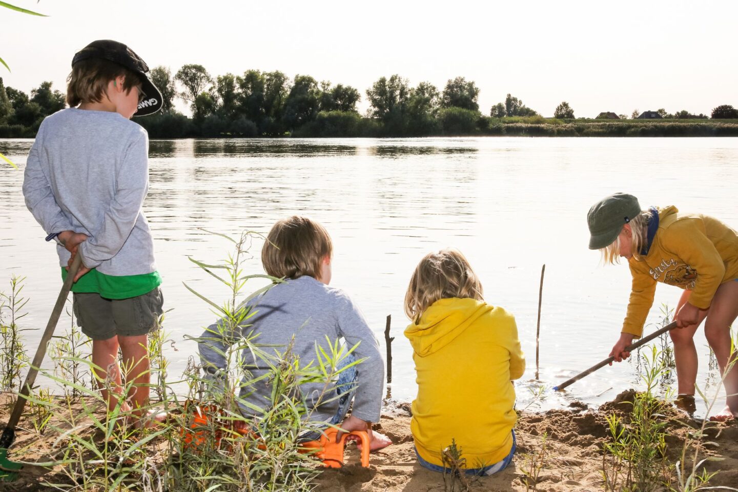 Vier Kinder spielen am Elbstrand im Wasser an der Freiluftschule Bunthausspitze.