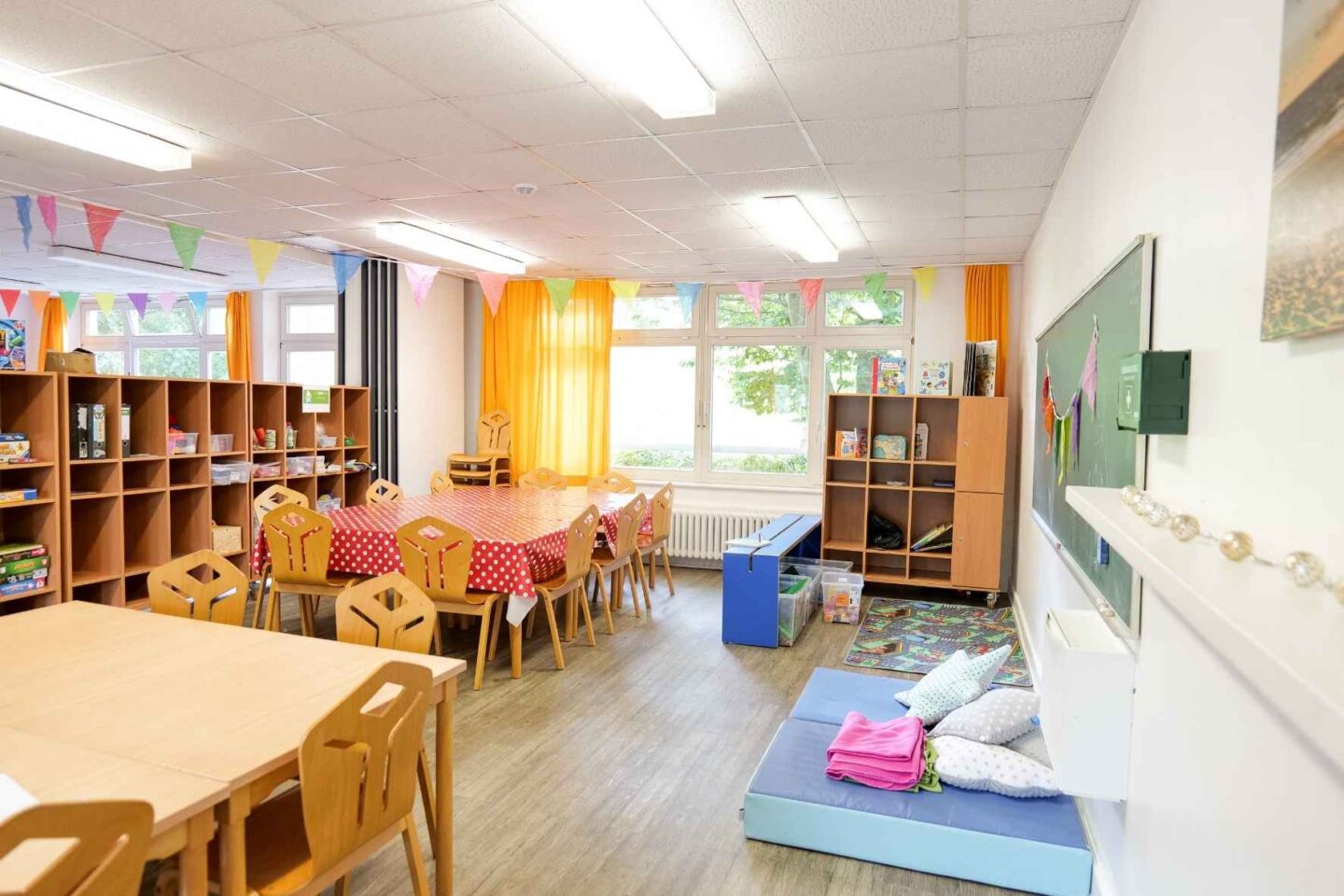 Heller Gruppenraum in der Freiluftschule Bunthausspitze mit Tischen und einer Leseecke.