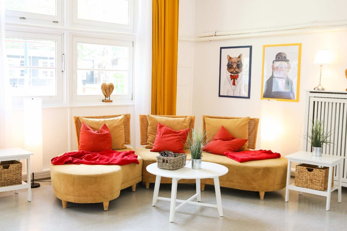 Gemütliche Leseecke mit einem großen Sofa, Kissen, Decken einem Couchtisch und bunten Bildern an der Wand in der Freiluftschule Fischbeker Heide.