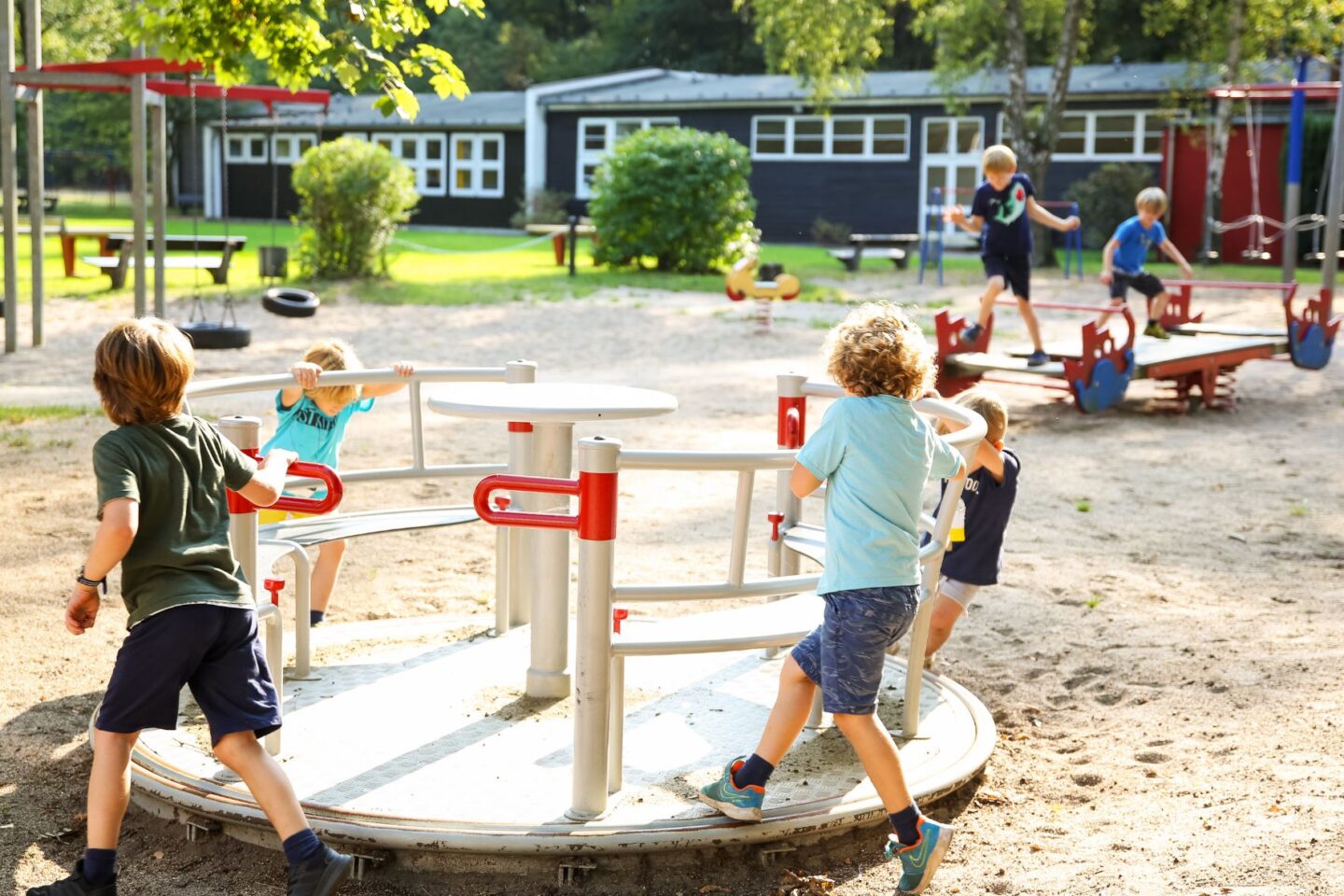 Gruppe von Kindern spielen auf einem Dreh-Karussell auf den Außengelände der Freiluftschule Fischbeker Heide.
