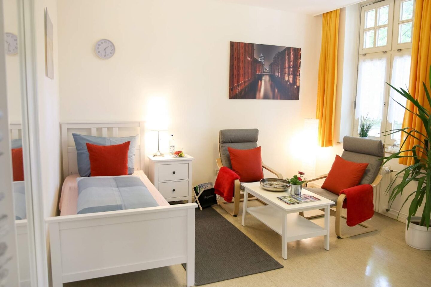 Helles, gemütliches Zimmer für die Betreuungsperson mit Einzelbett und einer Sitzecke mit zwei Stühlen und Couchtisch in der Freiluftschule Wittenbergen.