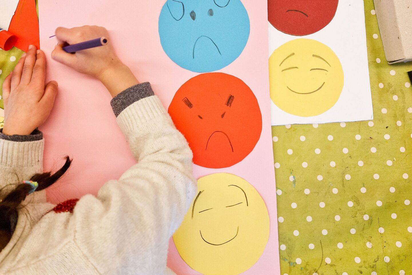 Kind malt bunte Smiley-Gesichter auf ein großes Blatt Papier,