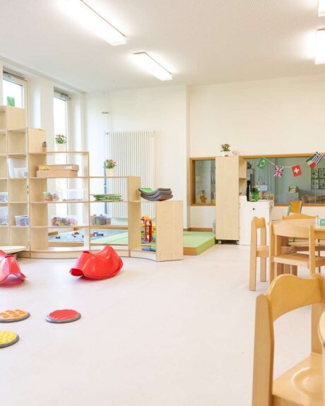 Ein lichtdurchfluteter Gruppenraum der Kita Barlsheide mit einer Vielzahl an Spielmaterialien und Kinderstühlen, perfekt für kreative Aktivitäten.