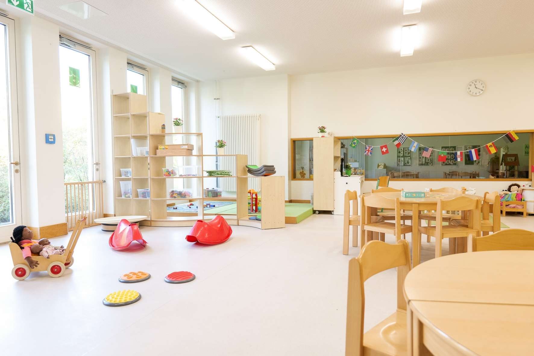 Ein lichtdurchfluteter Gruppenraum der Kita Barlsheide mit einer Vielzahl an Spielmaterialien und Kinderstühlen, perfekt für kreative Aktivitäten.