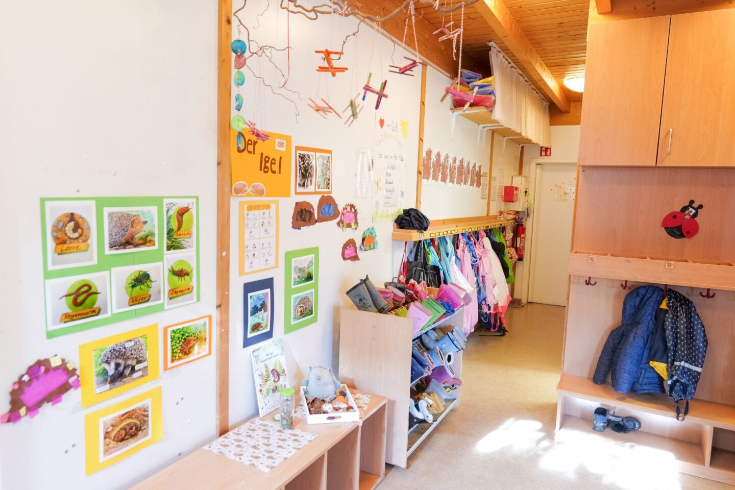 Helle und farbenfrohe Garderobe der Kita Eckerkoppel mit liebevoll gestalteter Wanddekoration und Platz für Jacken und Taschen.