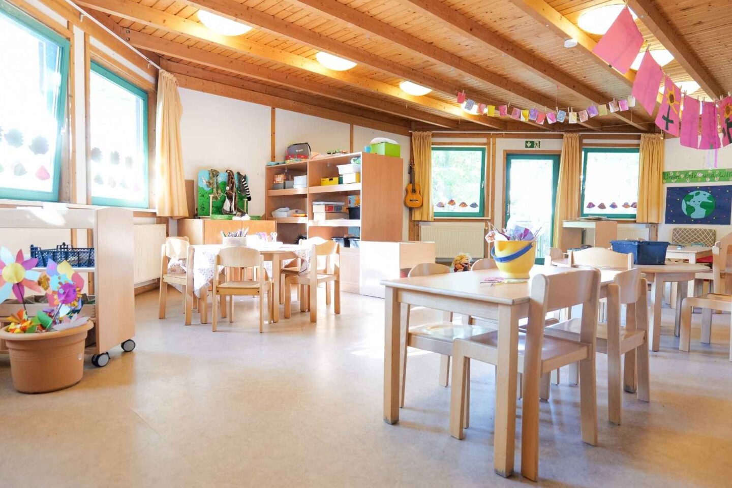 Heller Gruppenraum der Kita Eckerkoppel mit Holzdecken, Basteltischen und kreativen Materialien.
