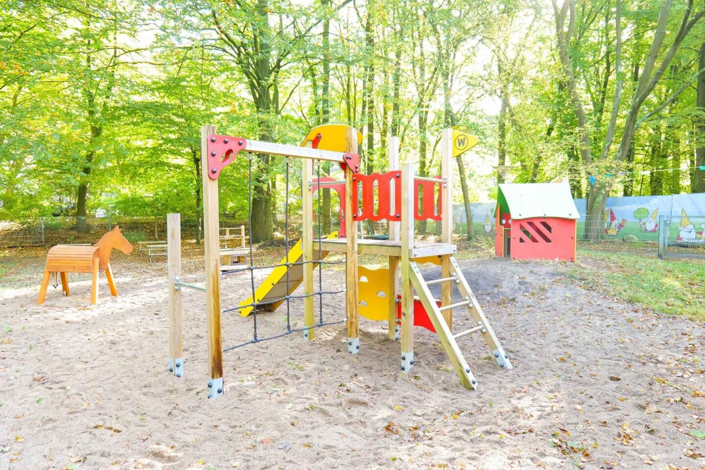 Spielplatz der Kita Franzosenkoppel mit buntem Klettergerüst und natürlicher Umgebung im Wald.