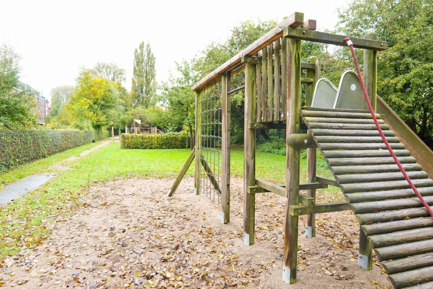 Holz-Spielplatz mit Klettergerüst und Sandfläche in der Kita Osterbrook