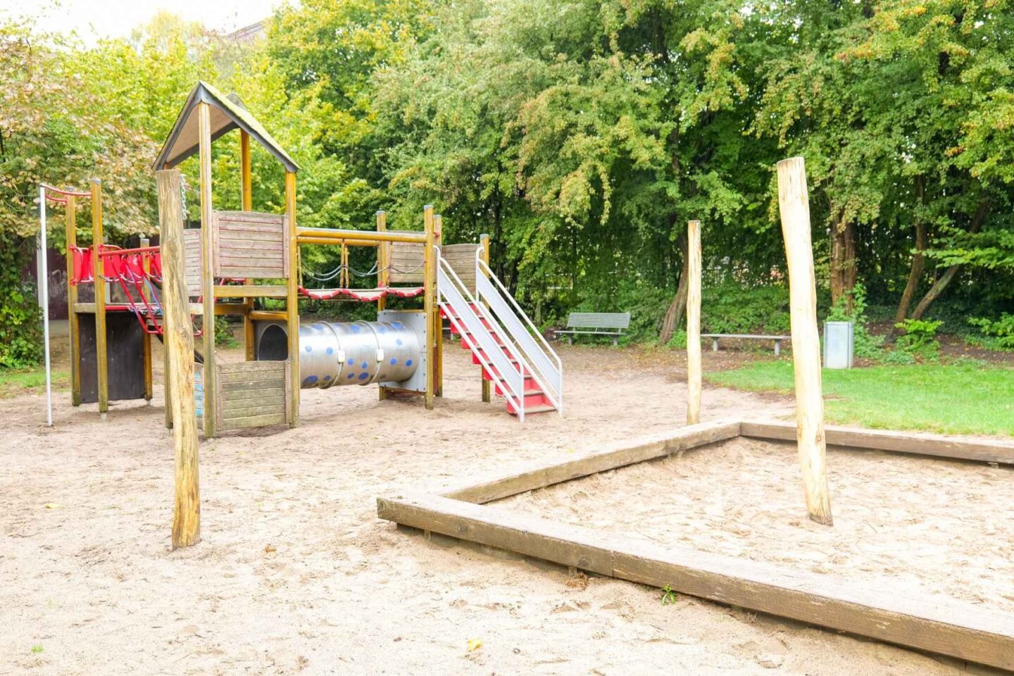 Spielbereich der Kita Osterbrook mit Kletterelementen aus Holz und Sandkasten