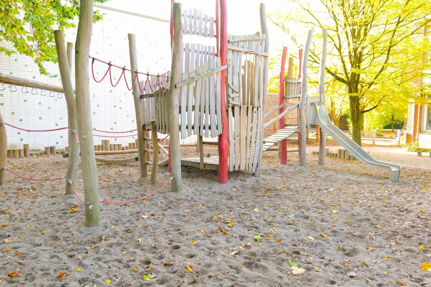 Großes Klettergerüst aus Holz mit vielen Spielelementen und einer Rutsche auf dem Außengelände der Kita Redder.