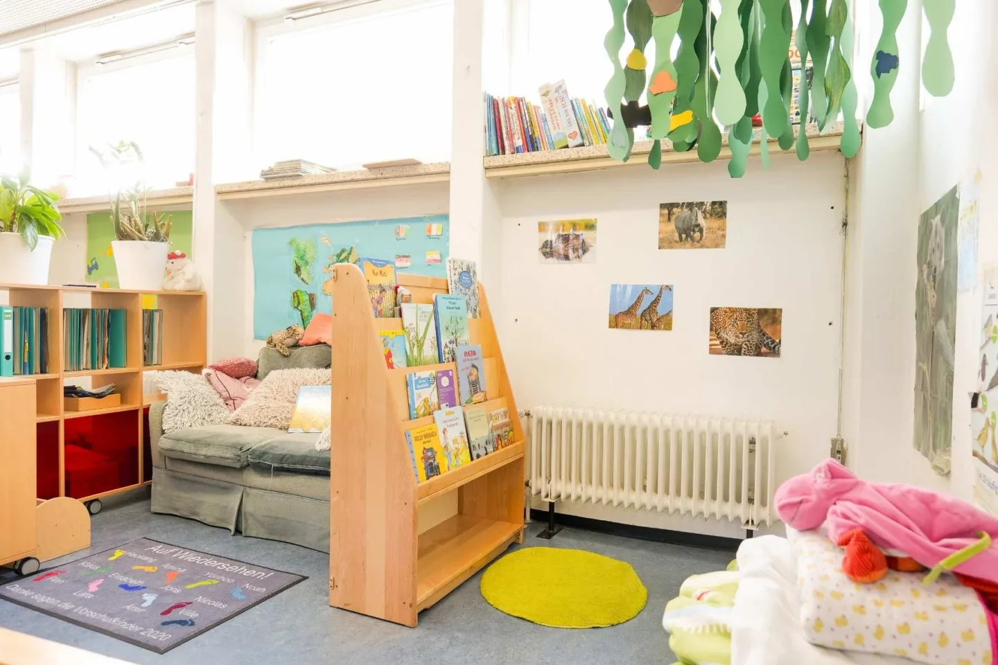 Helle, gemütliche Leseecke in der Kita Redder mit einem gemütlichen Sofa und einer kleinen Kuscheldecke mit vielen Decken und Kissen.