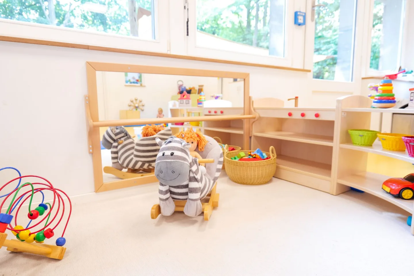 Heller Spielbereich der Krippe in der Kita Rungwisch mit Spielsachen und einem kleinen Schaukelpferd.