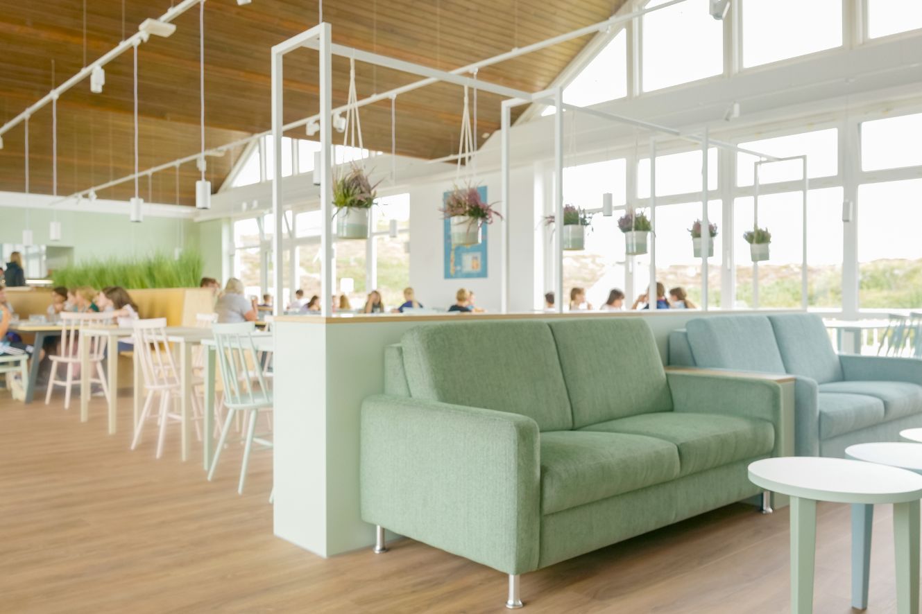 Mensa in unserer Strandperle auf Sylt: gemütliche Sofaecke sowie mehrere Tischgruppen mit Stühlen zum entspannten Essen.